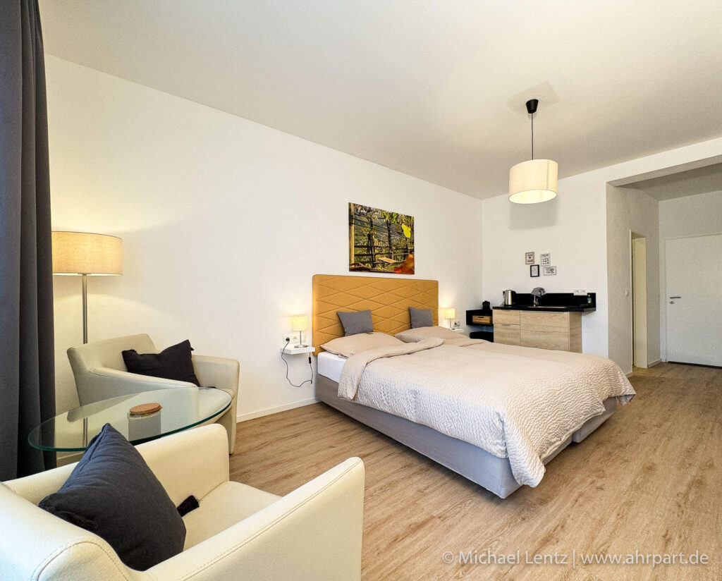 Großes bequemes Doppel Boxspringbett sowie gemütliche Sitzgruppe und die Cooffee Kitchen in einem Standard Doppelzimmer. Coffee Kitchen mit Kaffeemaschine, Wasserkocher, Minibar-Kühlschrank sowie Besteck und Geschirr, für einen guten Start in den Tag, im AHRPART Hotel