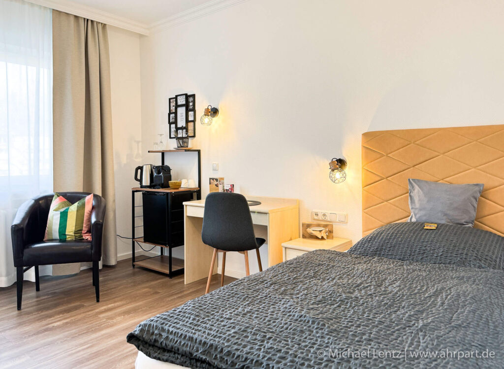 Großes gemütliches Boxspringbett, Schreibtisch mit Sitzgelegenheit sowie Coffee Kitchen und ein bequemer Sessel zum ausruhen.