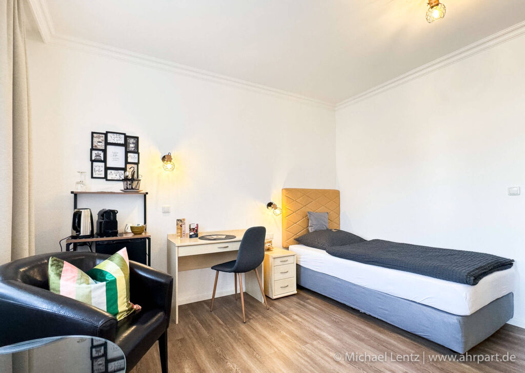 Großes gemütliches Boxspringbett, Schreibtisch mit Sitzgelegenheit sowie Coffee Kitchen und ein bequemer Sessel zum ausruhen.