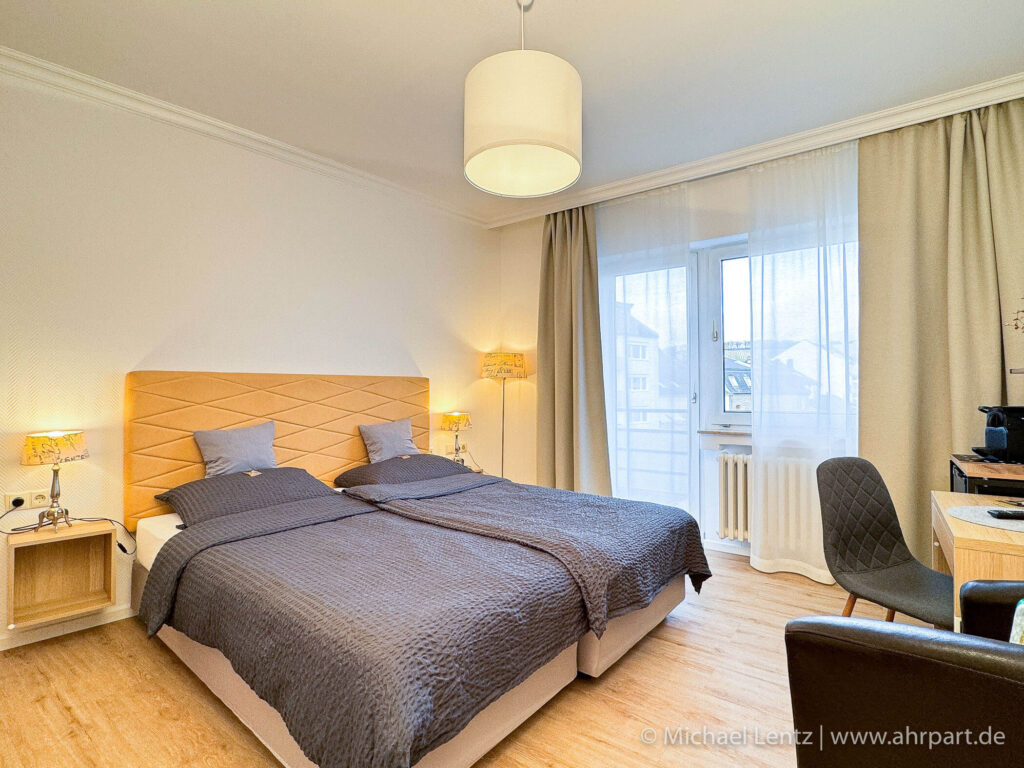 Großes Doppel Boxspringbett sowie Sitzgelegenheit und Schreibtisch im Standard Doppelzimmer